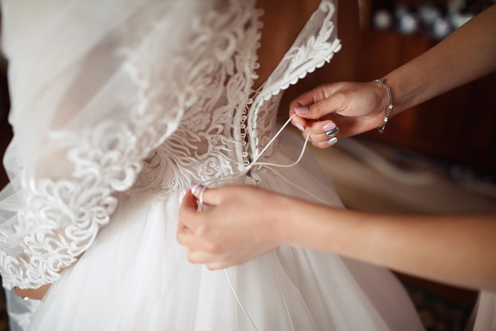The witness at the wedding helps to lace up the corset for the bride on the wedding dress